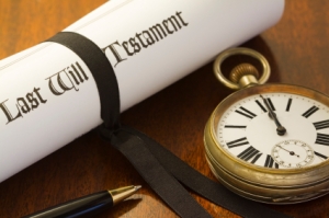 When your time comes to an end. A scroll of a Last Will & Testament, tied with a black ribbon on a mahogany desk, with pocket watch set to midnight: the end of time.
